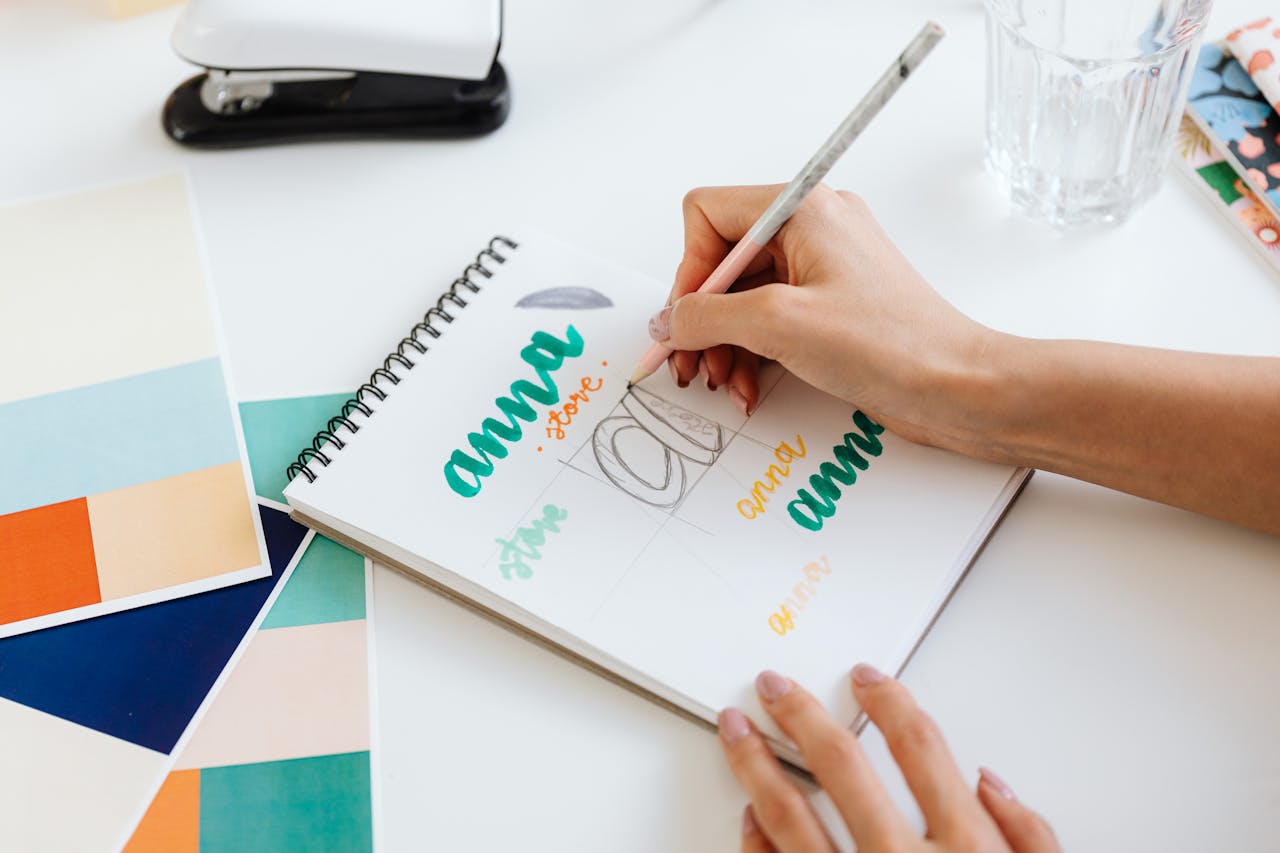 Close-up of a person drawing on a notepad surrounded by colorful swatches.